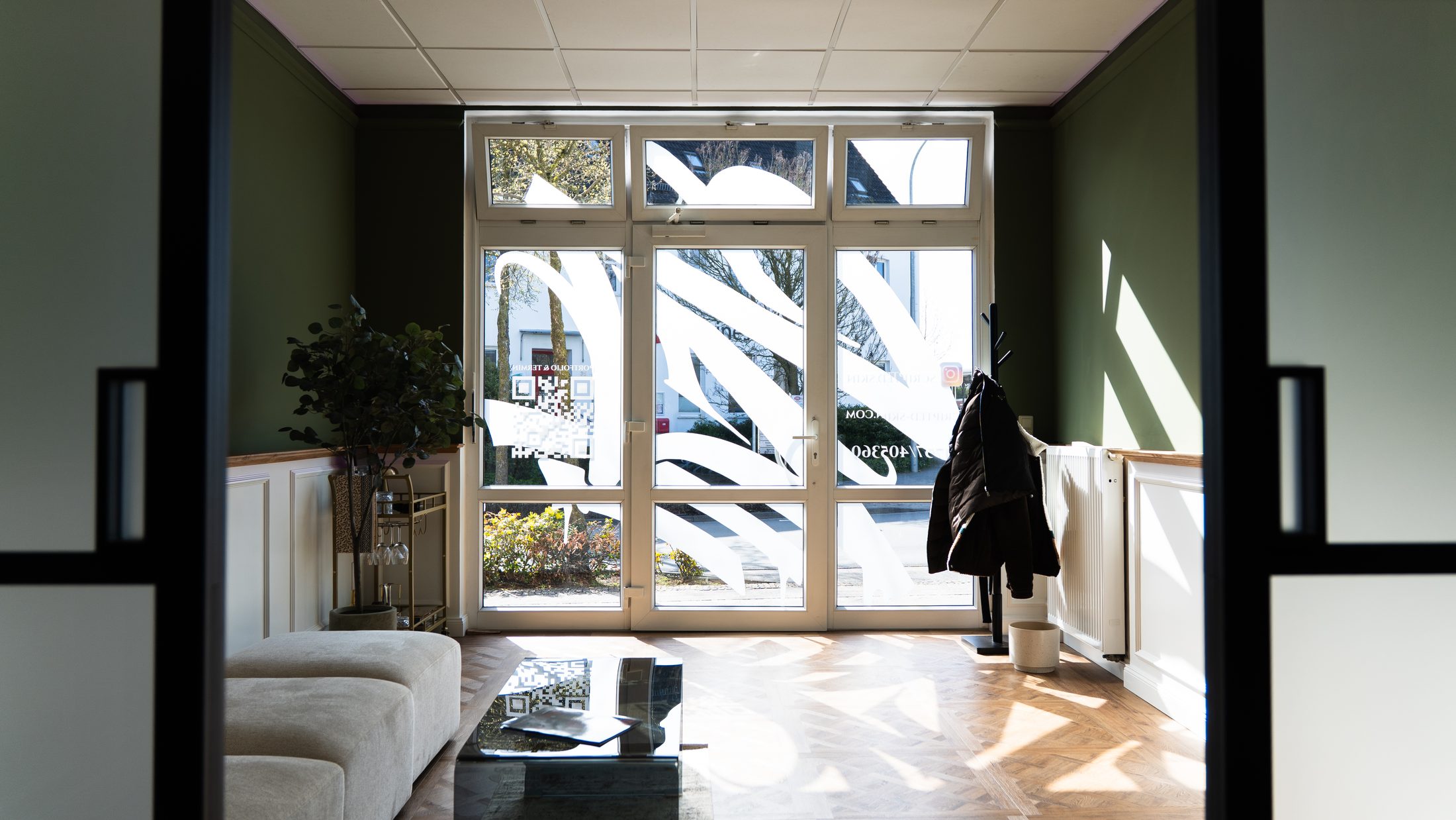 Heller Wartebereich mit grüner Wand und großem Fenster