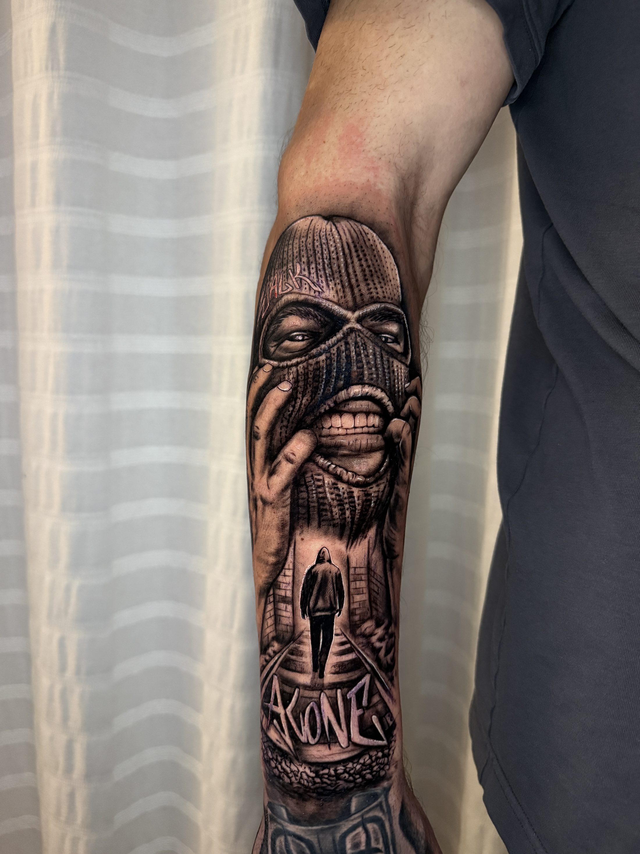 Vermummter Kopf mit Sturmhaube, Kapuzenfigur in einer Gasse und Graffiti-Schriftzug ALONE, Black & Grey Realistic auf dem Unterarm